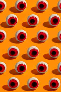 Artificial eyeballs pattern on bright orange background. 
