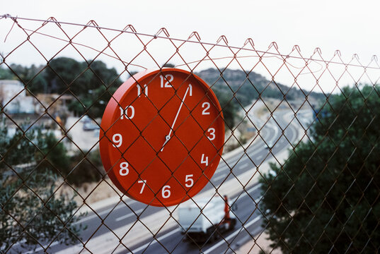 clock hanging from a chain-link fence, 35mm film
