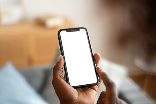 Unrecognizable man using smartphone with blank white screen at home