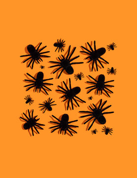 Black spiders pattern. Halloween decorations on orange background.