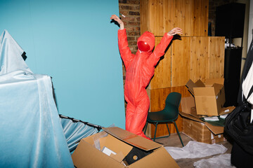 Person in Red Suit Performing Dance in Messy Room