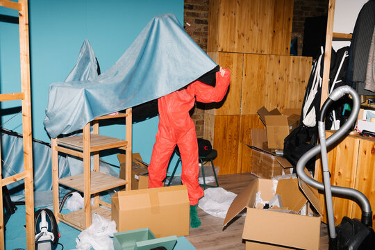 Person in Protective Suit Organizing a Cluttered Room