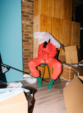 Person in Red Suit Sitting Among Moving Boxes