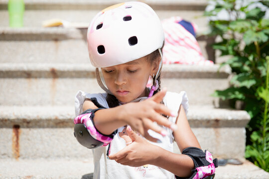 Young girl putting on elbow pads before roller blading