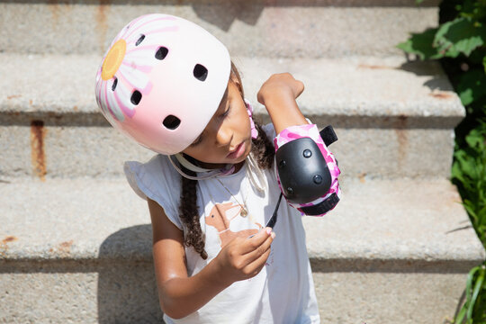 Young girl putting on her safety gear before roller blading