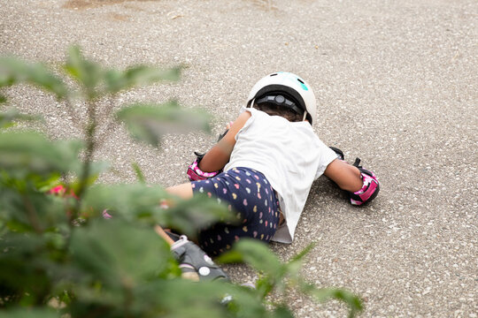 Child lying on the pavement after falling while roller blading.