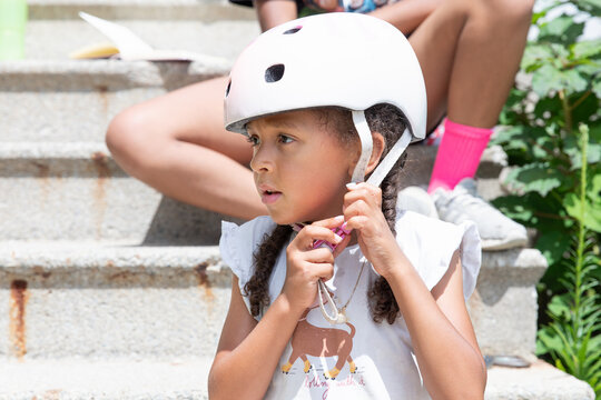Young girl putting on her helmet before roller blading