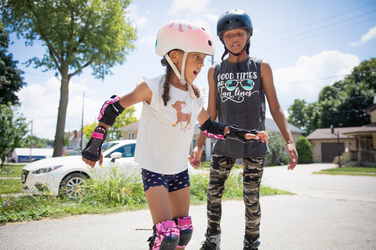 Teen teaching her young sibling to inline skate outside in the summer