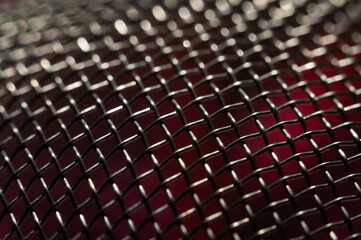 Fototapeta premium A close-up photo of a black wire mesh with a red background