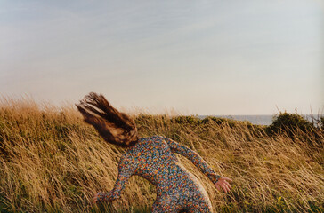 Woman in Floral Dress Running Through Windy Field