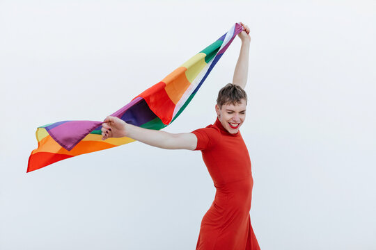 Excited androgynous model raising LGBT flag