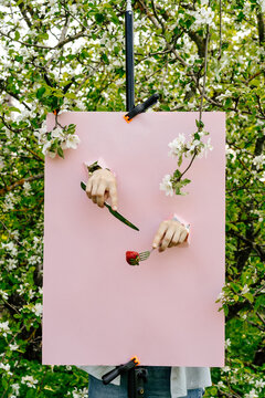 Hands emerging from pink poster holding knife and fork in garden