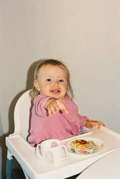 Baby girl eating waffle while breakfast with family.