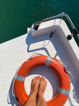 On board. Woman standing at the back of a boat with a lifebuoy ring.