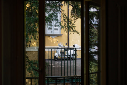 Fototapeta White vintage scooter parked outside a building window
