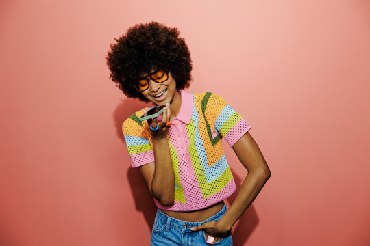 Stylish woman recording voice message on pink background