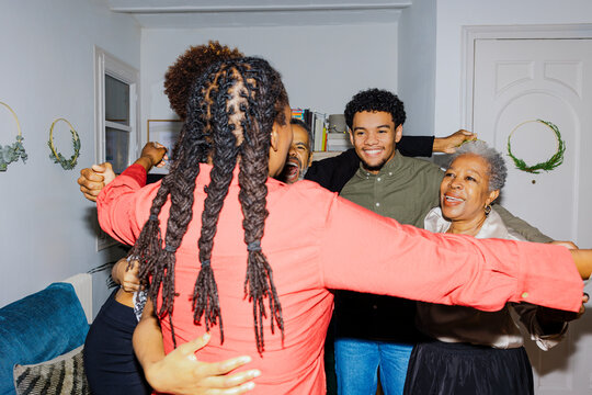 Happy multi generational family hugging at home