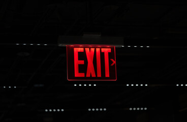 Red exit sign illuminated against dark background