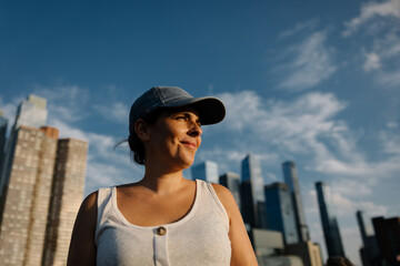 Woman in cap enjoying urban skyline under bright blue sky