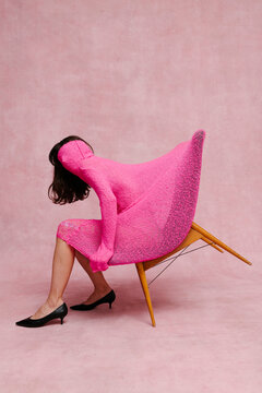 Woman in Artistic Pink Dress Resting on a Modern Chair
