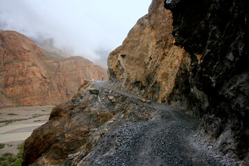 A man walking in distance on An extremely rugged and rocky track during bad weather