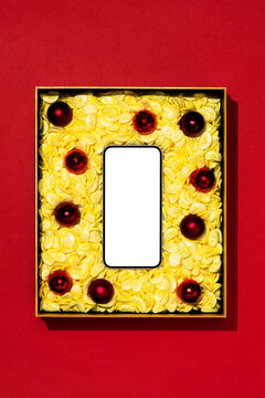 Smartphone and Christmas balls in a box  with yellow packaging foam