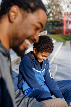 Happy son and father sitting on steps during sunny day