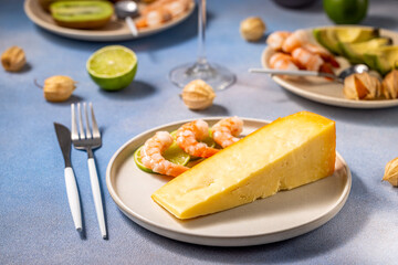 Wedge of cheddar cheese with shrimp and lime on a plate for appetizer