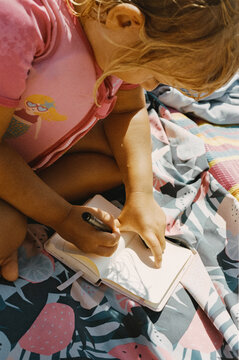 A child drawing at the beach in the life west