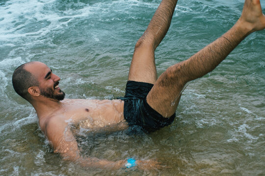 Young man smiling and playing in ocean waves 