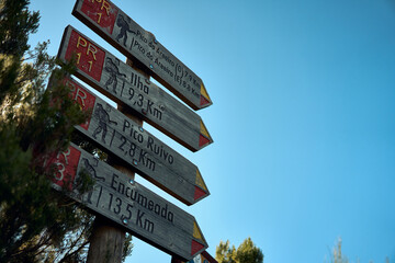 Trail signs indicate distances to nearby locations in a scenic outdoor environment during daylight hours