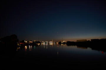 Obraz premium Evening calm over the tranquil river with city skyline illuminated by soft lights