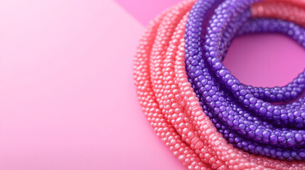 A close-up view of stylish bracelets, with a pink and purple background separated by a diagonal line.