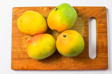 Mango fruit on cutting board isolated on white background, whole ripe yellow apple mango fruit