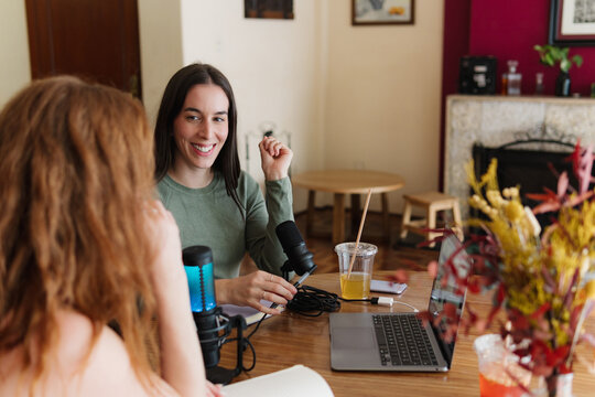 Women at home recording a podcast.