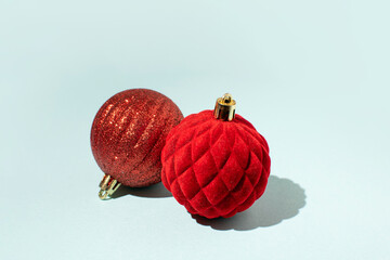 Two Christmas baubles of rich red color over ice blue colored background. Winter holidays greeting...