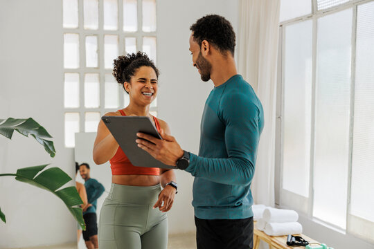 Personal trainer showing progress on tablet to a happy client