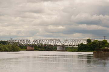 Obraz premium A quiet moment by the river showcasing a bridge under a cloudy sky