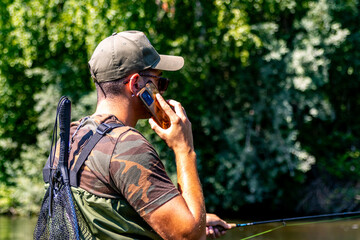 Man talking on phone while fishing in river