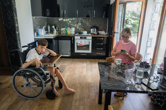 Woman and disabled child in wheelchair in the kitchen