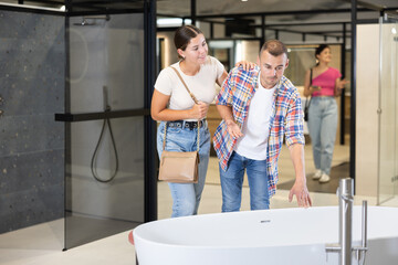 Couple of young man and woman choosing bath in hardware store