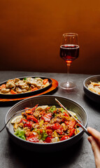 Elegant dinner setup with fresh salad, gourmet main course, and red wine