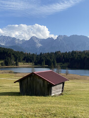 Alpine landscape of Bavaria with farm house and lake and mountains in background