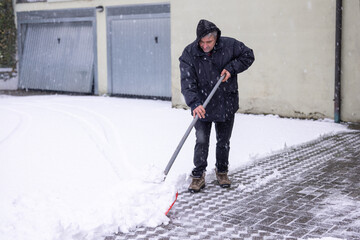Selective focus man shoveling snow from driveway during winter storm. World Snow Day. Snowstorm and...