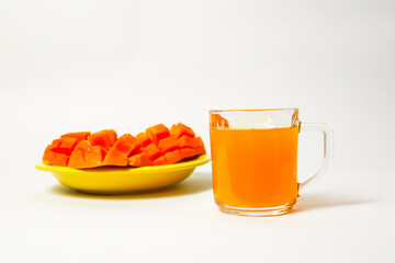 Glass of mango juice and sliced ​​mango slices on yellow plate isolated on white background