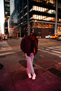 Man in casual outfit standing on a city street corner at dusk. NYC
