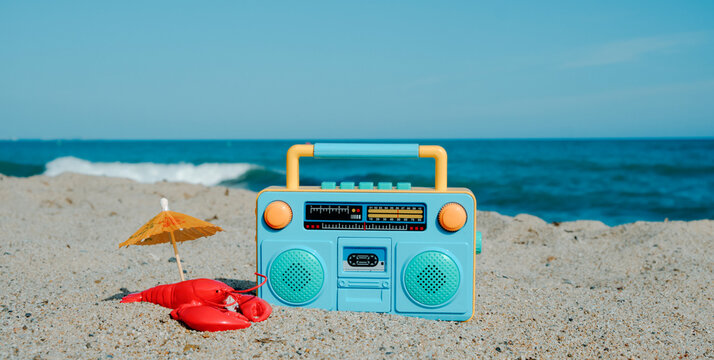 lobster, umbrella and boombox on the beach, panoramic format