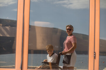 Mother and her disabled son in window reflection 