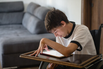 Teenage boy in wheelchair using tablet at home