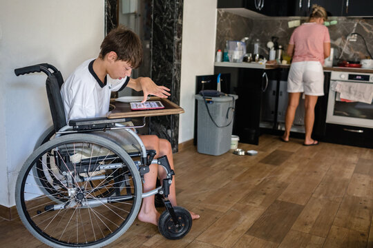 Teenage child in wheelchair and his mother in the kitchen